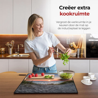 Mujer en la cocina preparando comida con la ayuda del protector de inducción playa y dunas.